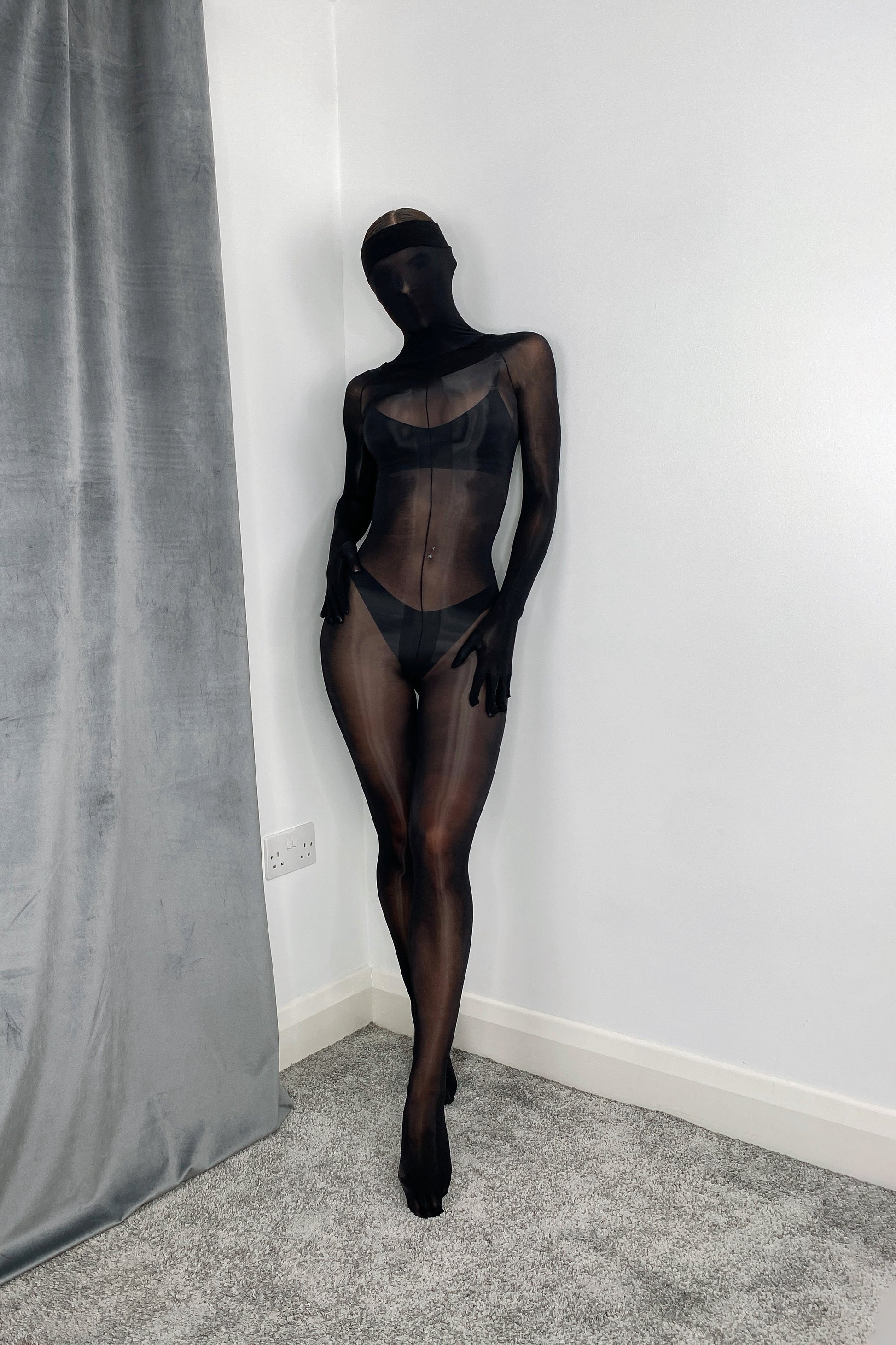 Close-up of black oil sheen on nylon bodystocking, gloves, and toe socks, high-gloss texture